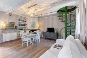 Una sala de estar moderna con comedor, una escalera espiral verde y un sofá blanco.