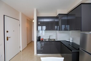 Eine moderne Küche mit dunklen Schränken, einem Edelstahlkühlschrank und einer weißen Arbeitsplatte.