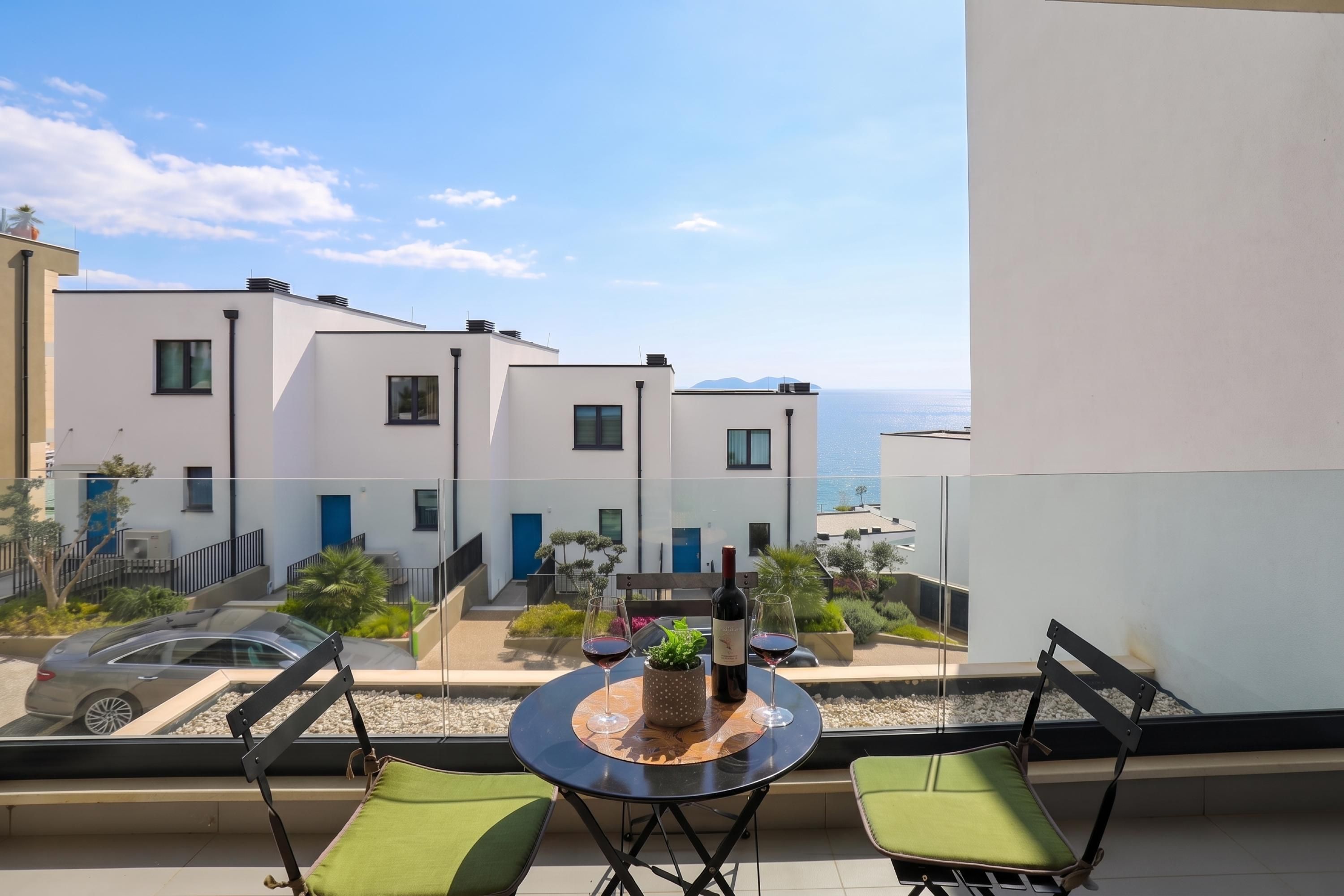 Un balcon avec une table ronde, deux chaises, une bouteille de vin et un verre de vin.