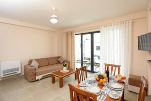 Ein Wohnzimmer mit einer Couch, Esstisch, Stühlen und einem Fernseher.
