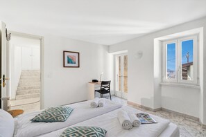 A hotel room with a bed, a desk, a chair, a window with a view, and a staircase. - Charm Apartments Lake View in Aldesago, Aldesago (Lugano), Switzerland (Aldesago (Lugano))