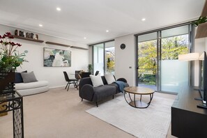 Una sala de estar moderna con un sofá, sillas, una mesa de centro y un comedor.