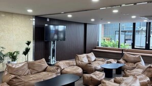Un'area lounge moderna con divani in pelle, un tavolino centrale e un televisore a schermo piatto montato a parete.