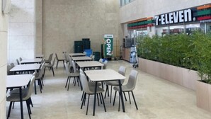Un negozio 7-Eleven con interni moderni, inclusi tavoli e sedie disposti per consumare cibo all'interno.