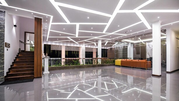 A modern lobby with a geometric ceiling design, a staircase, and a reception area with seating. - Madu River Reach (Balapitiya)