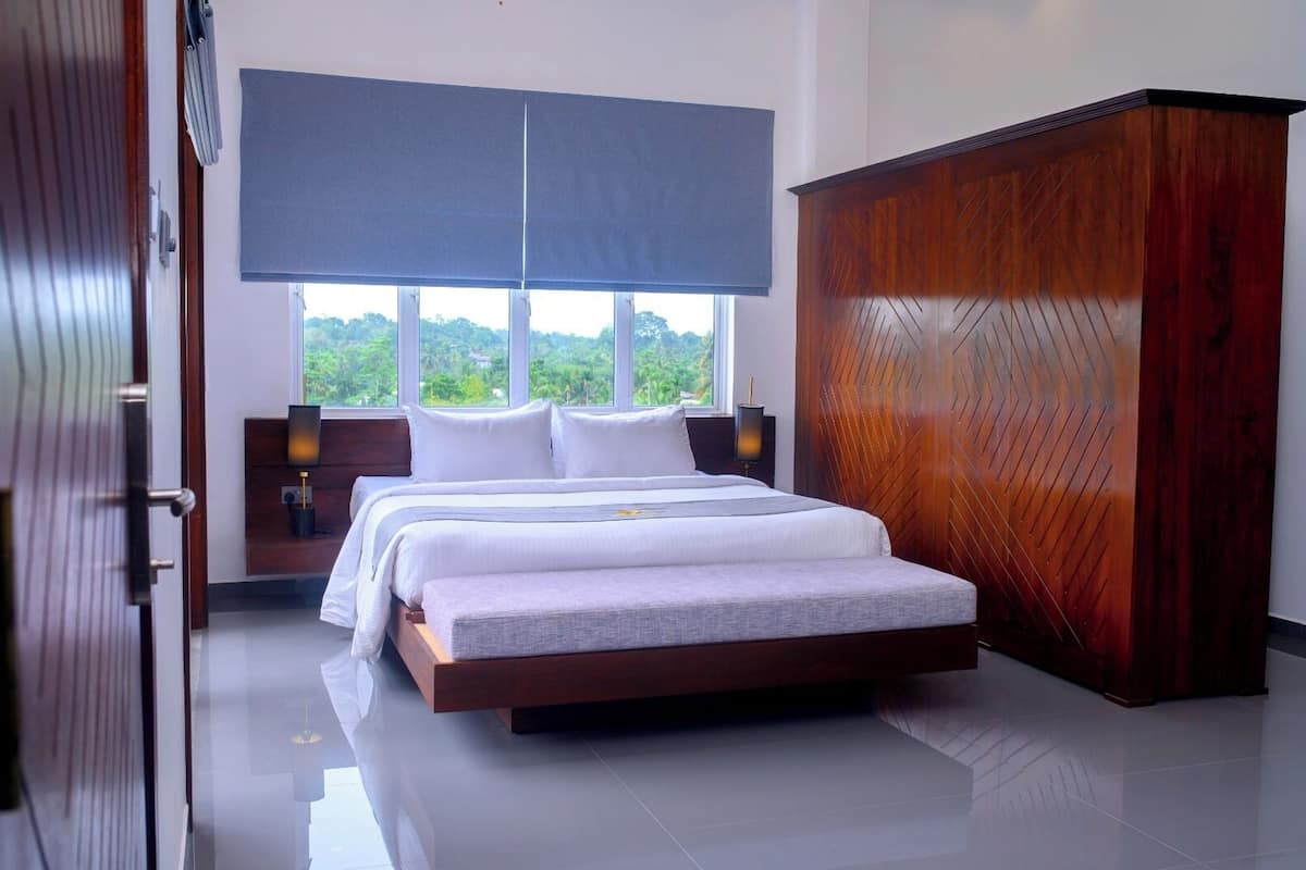 Un dormitorio con una cama grande, un armario y vistas a zonas verdes por la ventana.