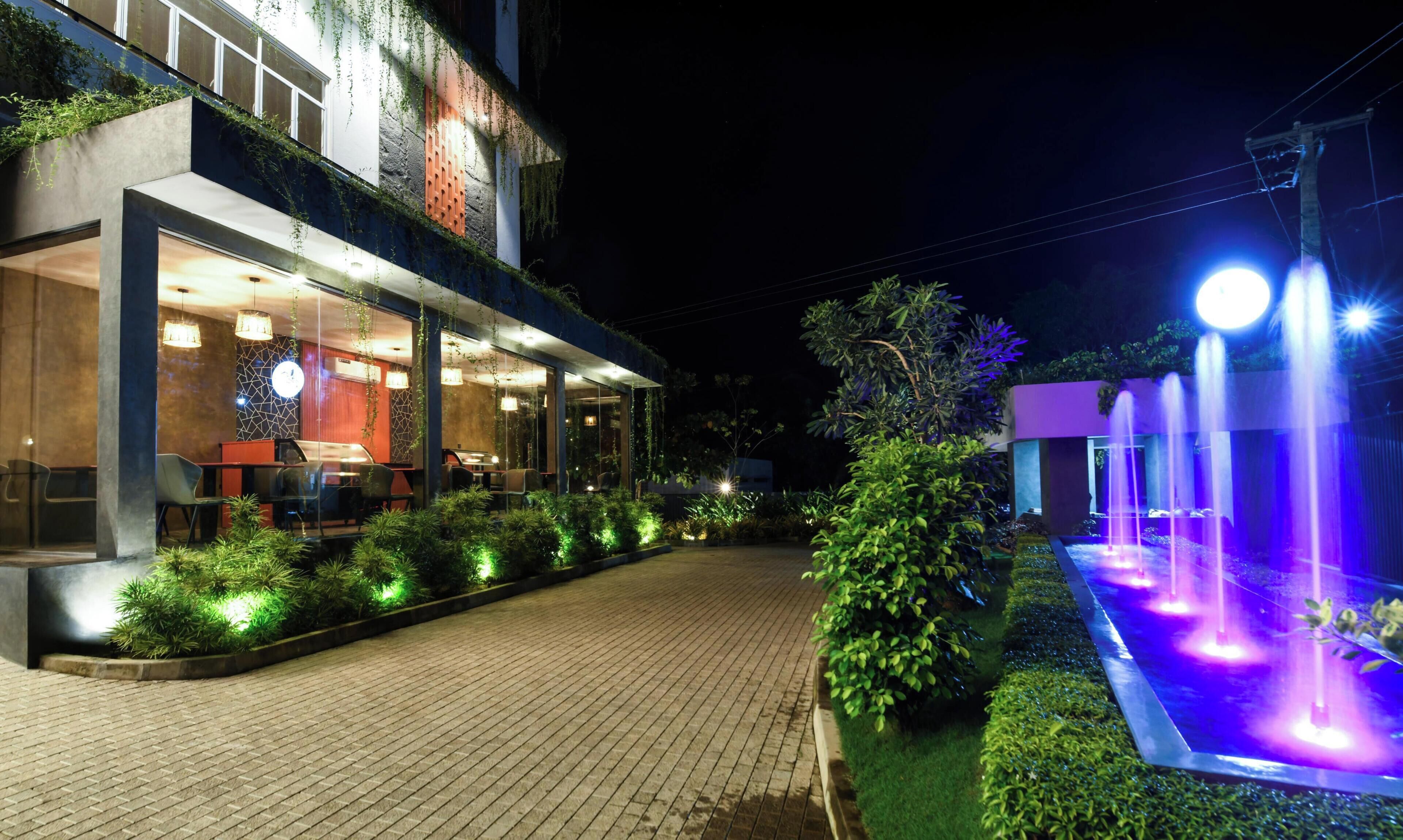 A modern building with a glass facade, outdoor seating, and a water feature.