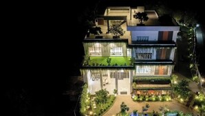 A modern multi-story building with a well-lit entrance, a visible outdoor seating area, and a rooftop garden. - Madu River Reach (Balapitiya)