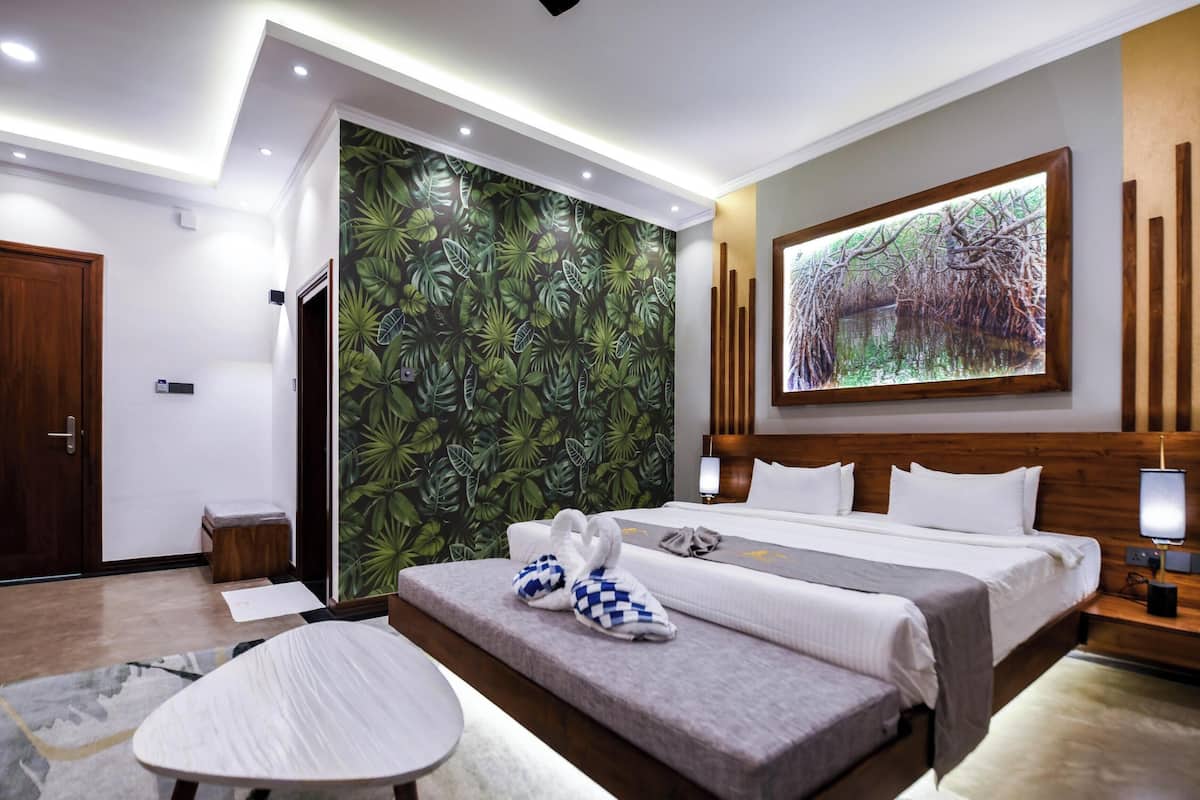Una habitación de hotel moderna con una cama, una zona de estar, un mural grande en la pared y un cuadro.