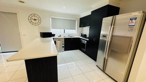 A modern kitchen with a central island, a built-in oven, a refrigerator, and a microwave. - Peaceful corner retreat|Park Side | 3 Bed, 2 Bath (Cranbourne West)