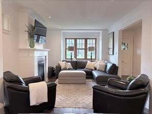 Ein modernes Wohnzimmer mit Kamin, Ledersofas, einem großen Fenster und einem Flachbildfernseher.