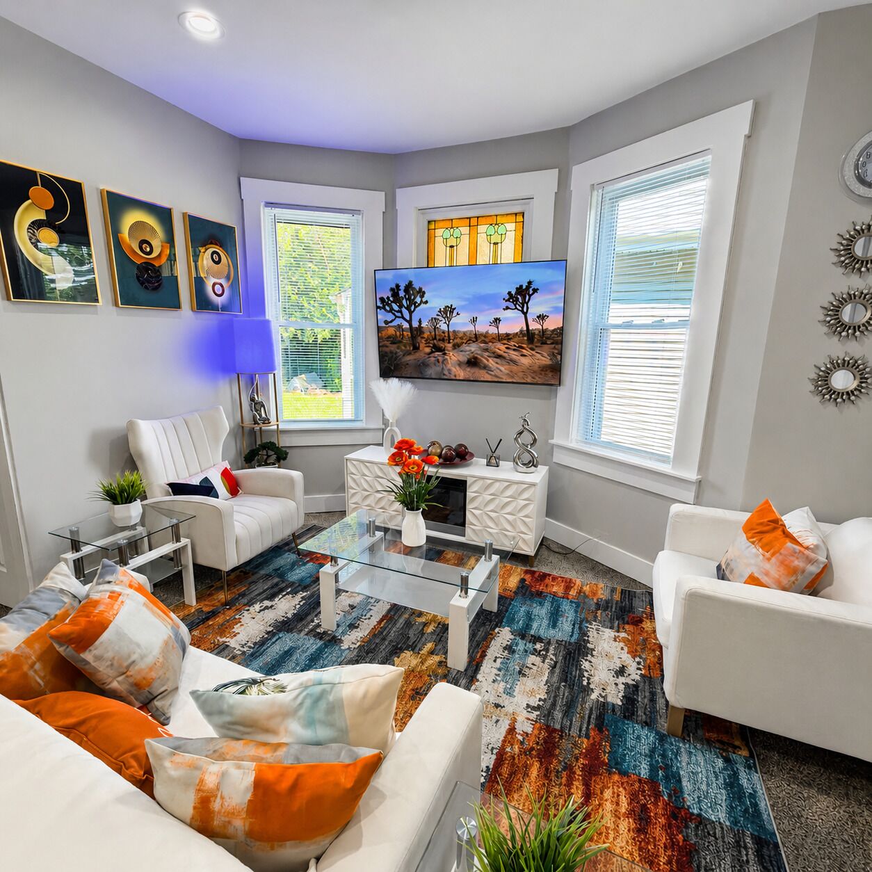 A modern living room with a sofa, armchair, coffee table, and a flat-screen TV.
