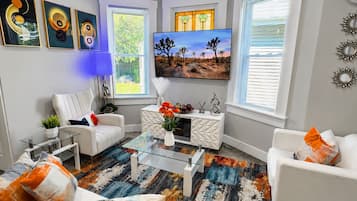 A modern living room with a sofa, armchair, coffee table, and a flat-screen TV.