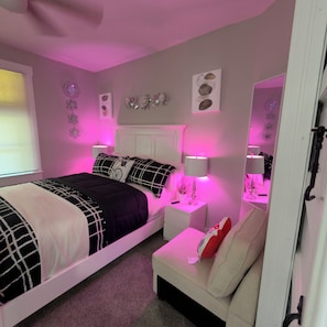 Een slaapkamer met een bed, nachtkastjes, een stoel en een spiegel.