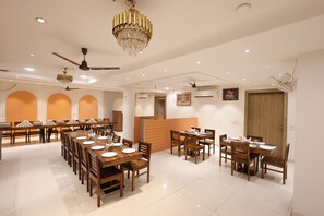 A spacious dining area with multiple tables, ceiling fans, and a chandelier.