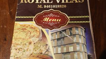 A menu cover for Hotel Royal Vilas with a building image and food items.