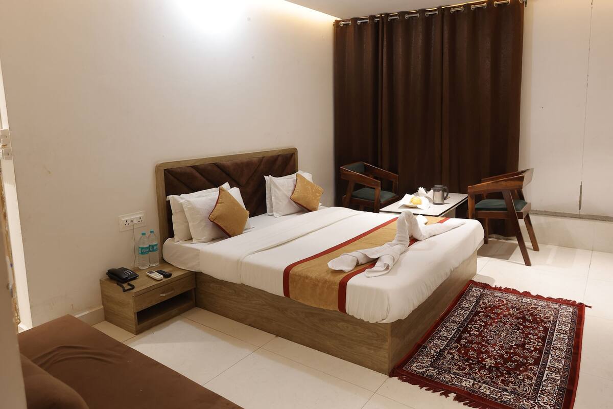 A hotel room with a bed, bedside table, chair, and a ceiling fan.