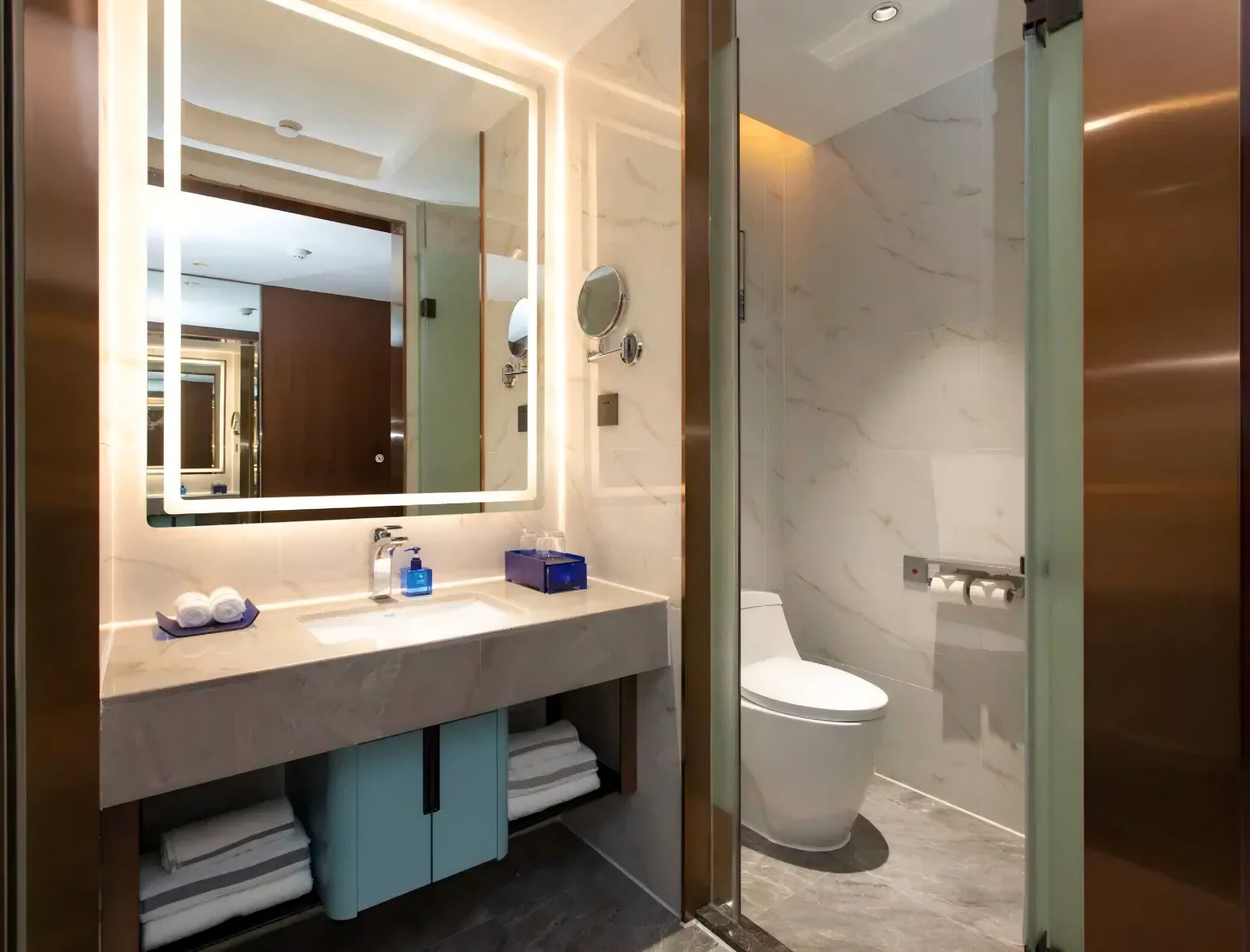 Une salle de bain moderne avec un grand miroir, un lavabo, des toilettes et une douche à parois de verre.
