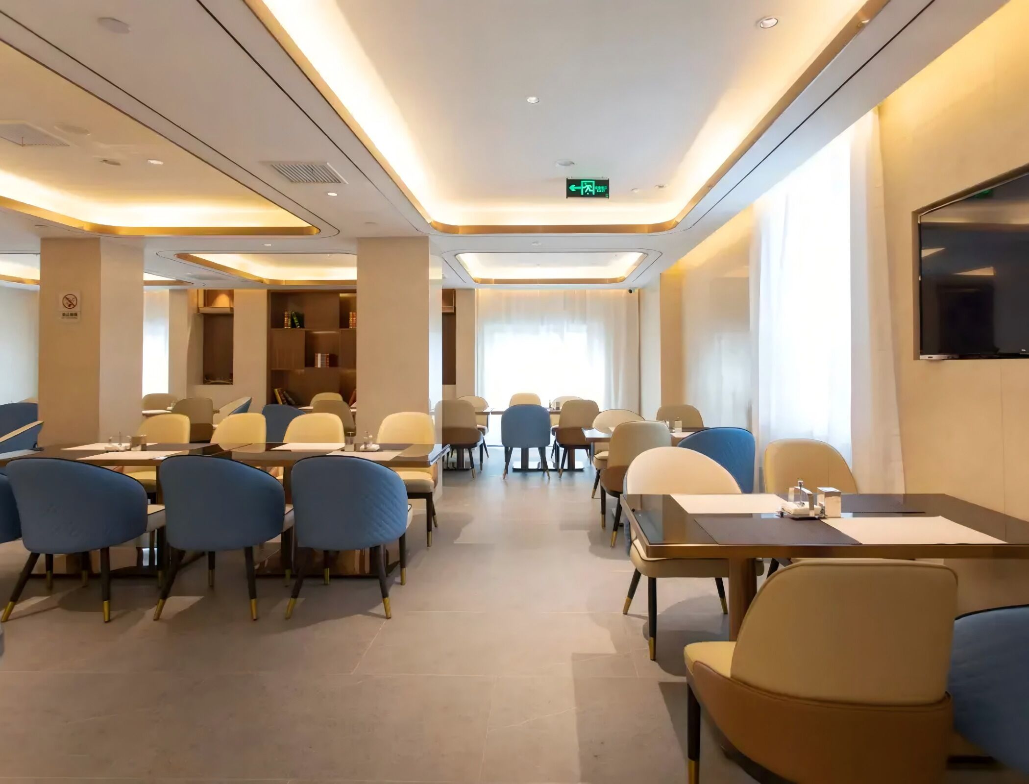 A hotel conference room with tables and chairs, a bookshelf, and a television on the wall.