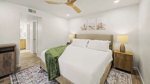 A bedroom with a bed, a ceiling fan, a nightstand with a lamp, and a wall-mounted artwork. - Central Scottsdale Haven Condo (Scottsdale)