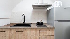 Modernilla designilla varustettu keittiö, jossa on ruostumattomasta teräksestä valmistettu jääkaappi, musta allas ja puinen kaappi.
