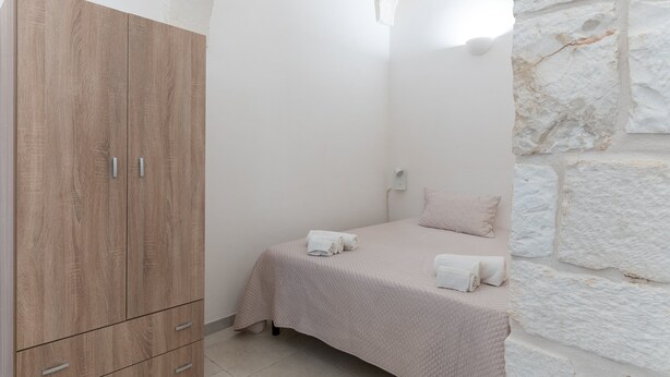 Une chambre à coucher avec un lit, une armoire en bois et un mur en pierre.