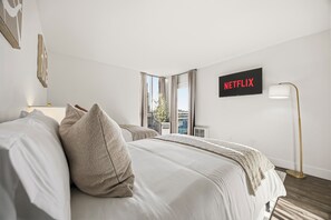 Una habitación de hotel con una cama, un cartel en la pared que dice 'NETFLIX' y una lámpara de pie.