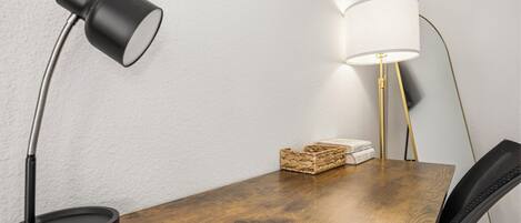 A wooden table with a black desk lamp and a floor lamp with a white shade.