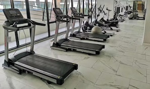 Ein Fitnessstudio mit mehreren Laufbändern, Gymbällen und Kraftgeräten.
