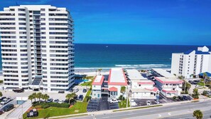Ein Hochhaus-Hotel mit Parkplatz, Blick auf den Strand und blauem Himmel.