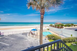 Ein Poolbereich mit Blick auf den Strand, einer Palme und einer Treppe.