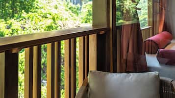 A wooden deck with a cushioned seating area, overlooking a lush green landscape.