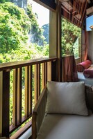 A wooden deck with a cushioned seating area, overlooking a lush green landscape.
