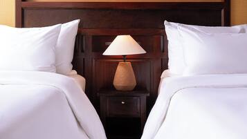 A hotel room with two beds, a nightstand with a lamp, and a wooden headboard.