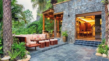 A stone building with a patio area featuring outdoor furniture and a view into the interior.