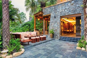A stone building with a patio area featuring outdoor furniture and a view into the interior.