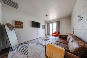 Ein Wohnzimmer mit einer Couch, einem Couchtisch, einem Fernseher und einem gemusterten Teppich.