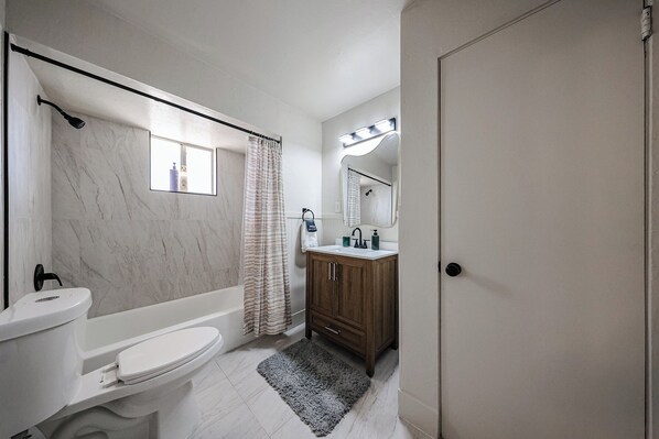 A bathroom with a toilet, bathtub, shower, vanity, and a mirror. - #1 Renovated Midtown Gem + Quiet + Budget Friendly (Phoenix)