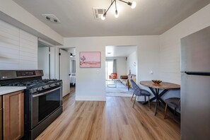 Eine moderne Küche mit einem LG-Herd, Holzböden, einem Essbereich mit rundem Tisch und Stühlen sowie einem Wohnzimmer mit Sofa und Couchtisch.