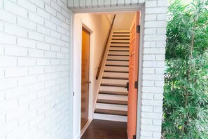 A staircase leading to a second floor, white brick walls, and a door at the top. - Harbor Home (Oldsmar)