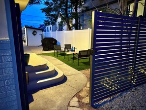 Takapiha, jossa on patio, ulkotila istumiseen, grilli ja portilla varustettu sisäänkäynti.