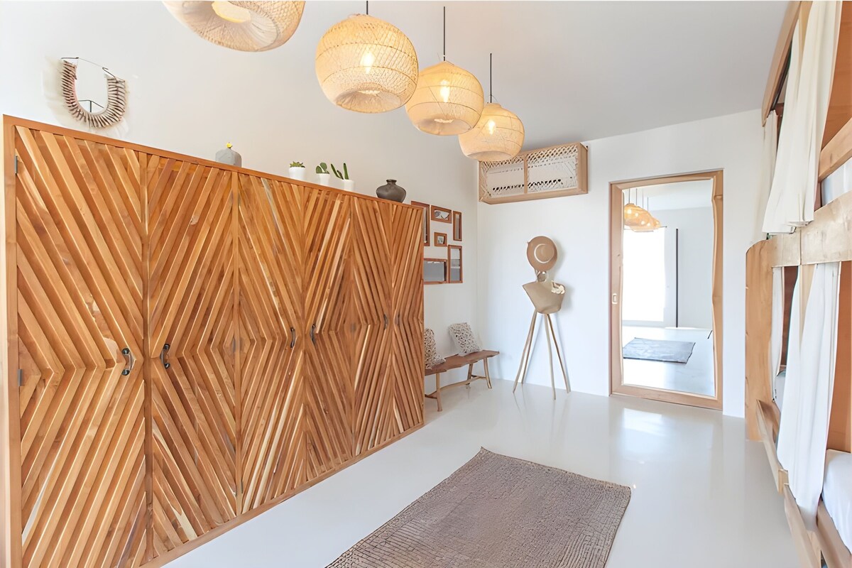 Decoração moderna com divisória de madeira, luminárias pendentes e um banco.