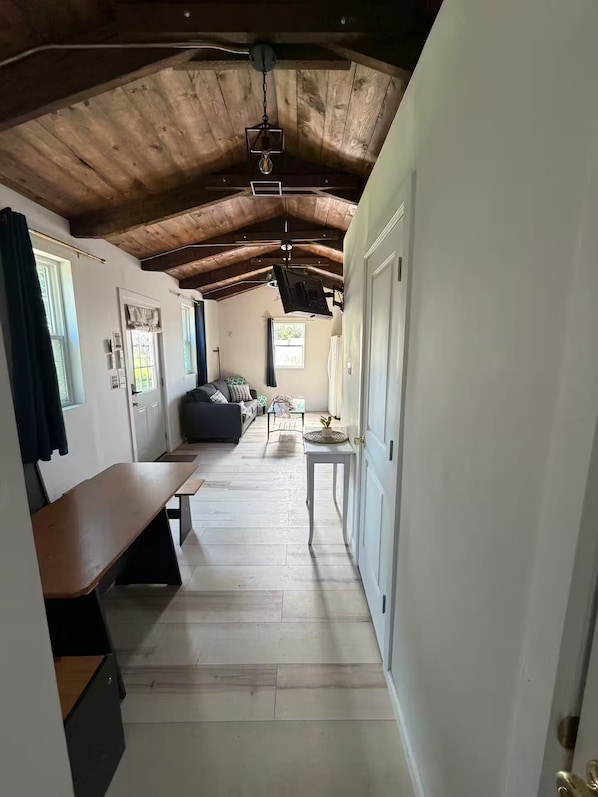 A rustic interior with a wooden ceiling, a bench, a sofa, and a small table.