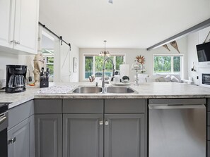A modern kitchen with a large island, double sinks, and a view of the outdoors.