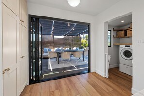 Eine moderne Küche mit integriertem Waschmaschine, ein Essbereich mit Glastür zu einer Außenpatio und eine Schiebetür zu einem überdachten Sitzbereich im Freien.