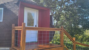 A small wooden house with a red door, a wooden deck, and a metal fence. - Peaceful country rustic glamping cottage- stargazing and mountain views (Saltville)