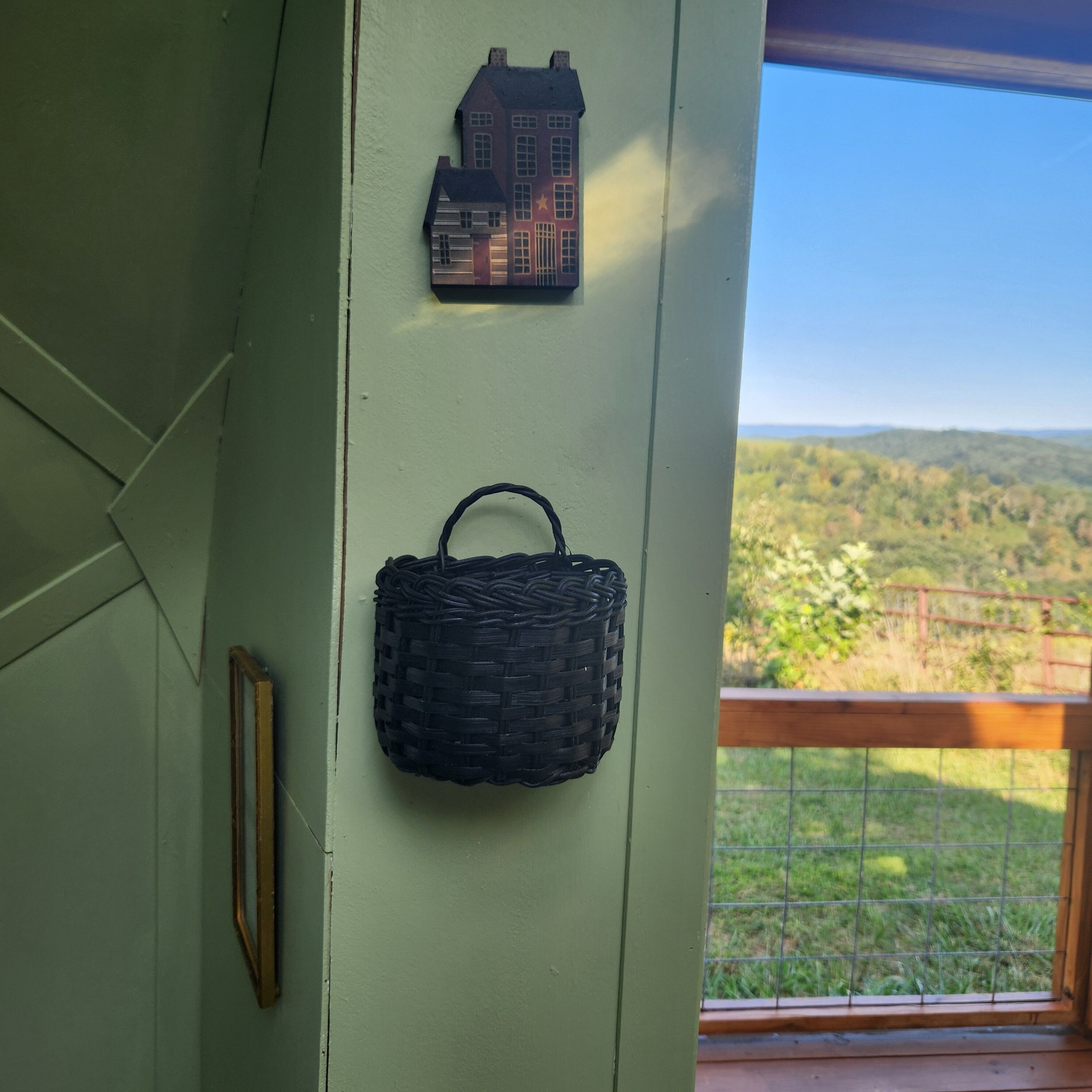 A wall with a house-shaped decoration and a woven basket.
