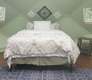 Una cama con una colcha estampada, una almohada y un adorno de pared.