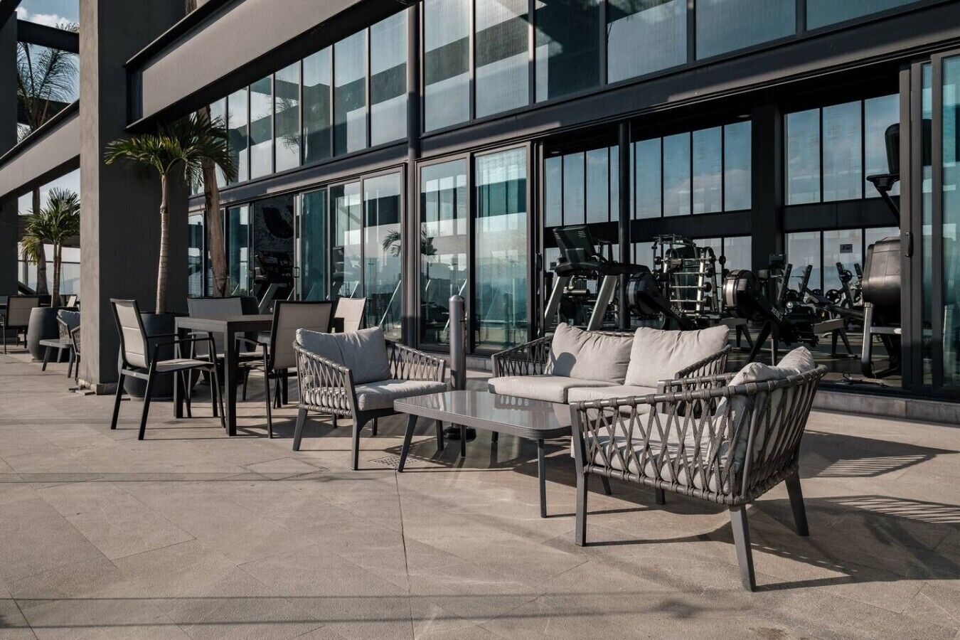 An outdoor seating area with modern furniture, large windows, and exercise equipment.