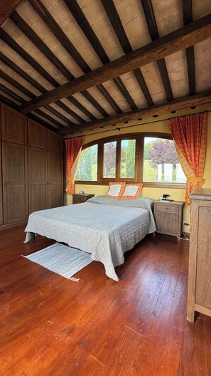 A bedroom with a bed, wooden wardrobe, nightstand, and a window with curtains. - Magical Umbrian Villa and Guest House with Pool (MONTECASTRILLI)